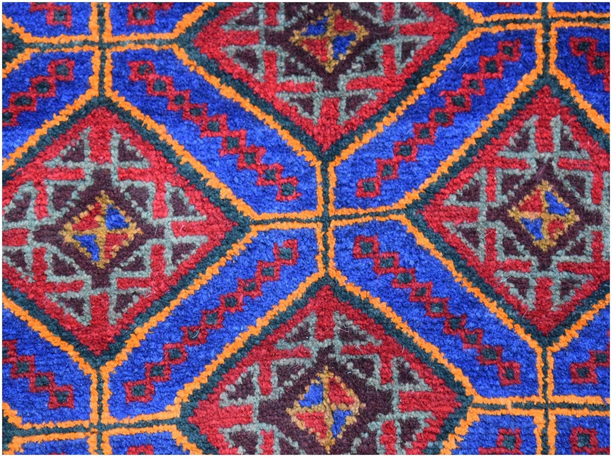 A vintage Afghan Baluch wool rug featuring a geometric pattern of red and blue diamonds.