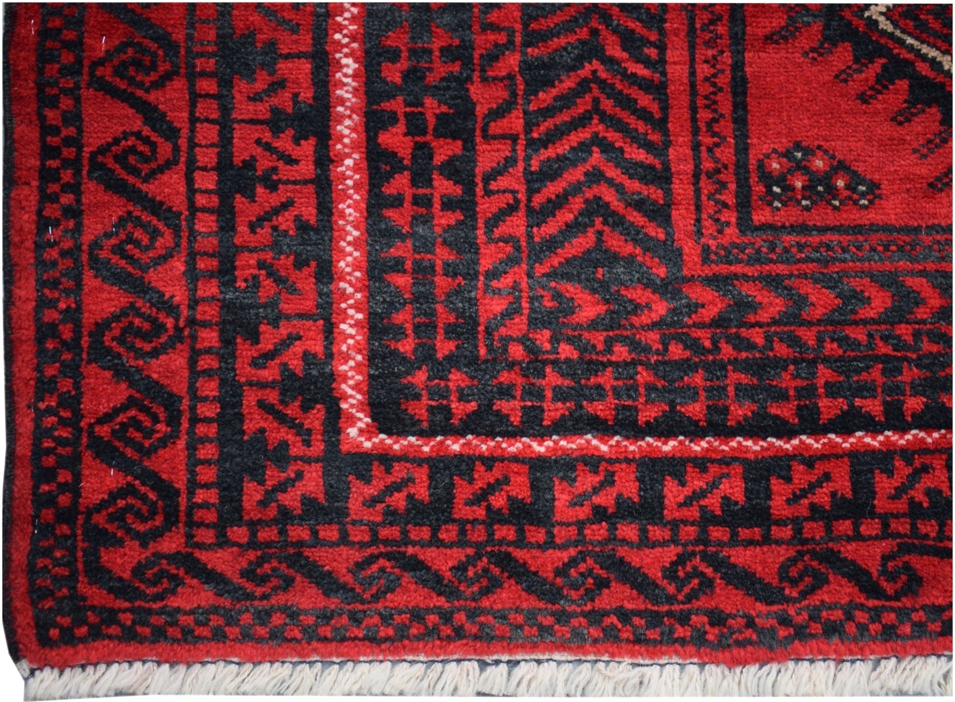 A vintage Afghan Baluch rug featuring traditional geometric patterns in red and black wool.
