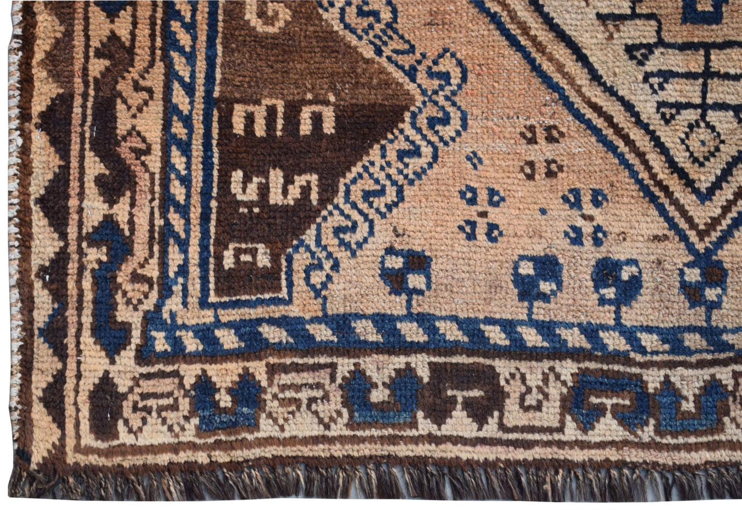 A vintage Afghan Baluch rug featuring geometric tribal patterns in brown, blue, and beige wool.