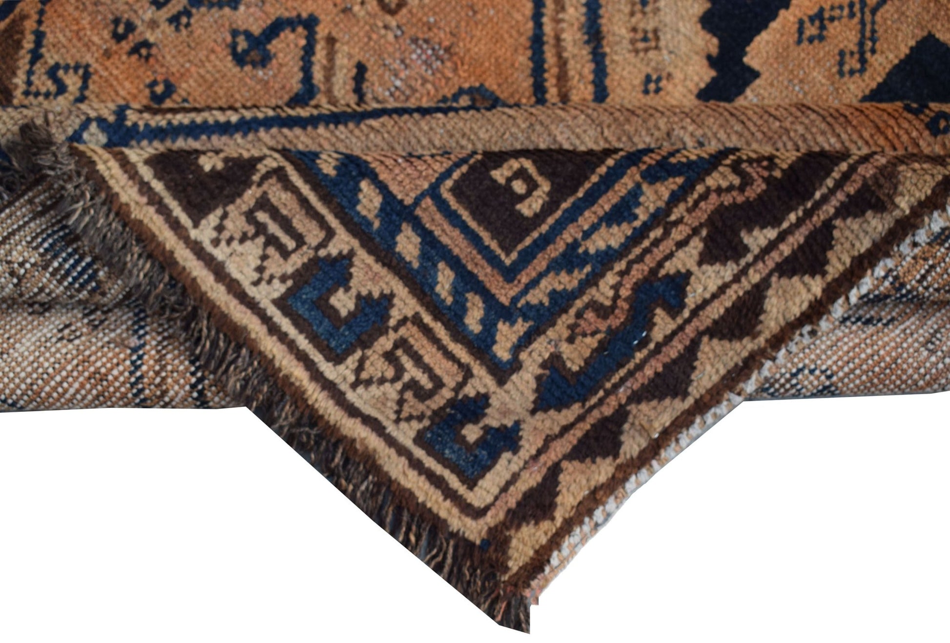 A corner of a vintage Afghan Baluch wool rug showing geometric patterns in blue and brown.