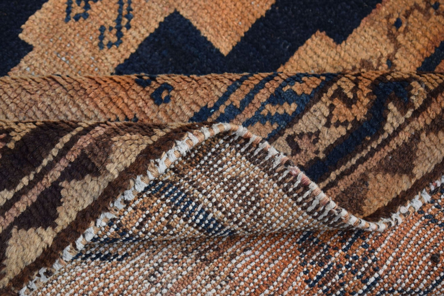 A vintage handmade Afghan Baluch rug featuring geometric patterns in shades of brown and blue.