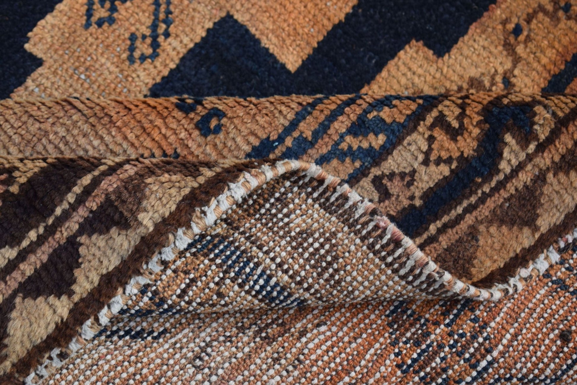A vintage handmade Afghan Baluch rug featuring geometric patterns in shades of brown and blue.