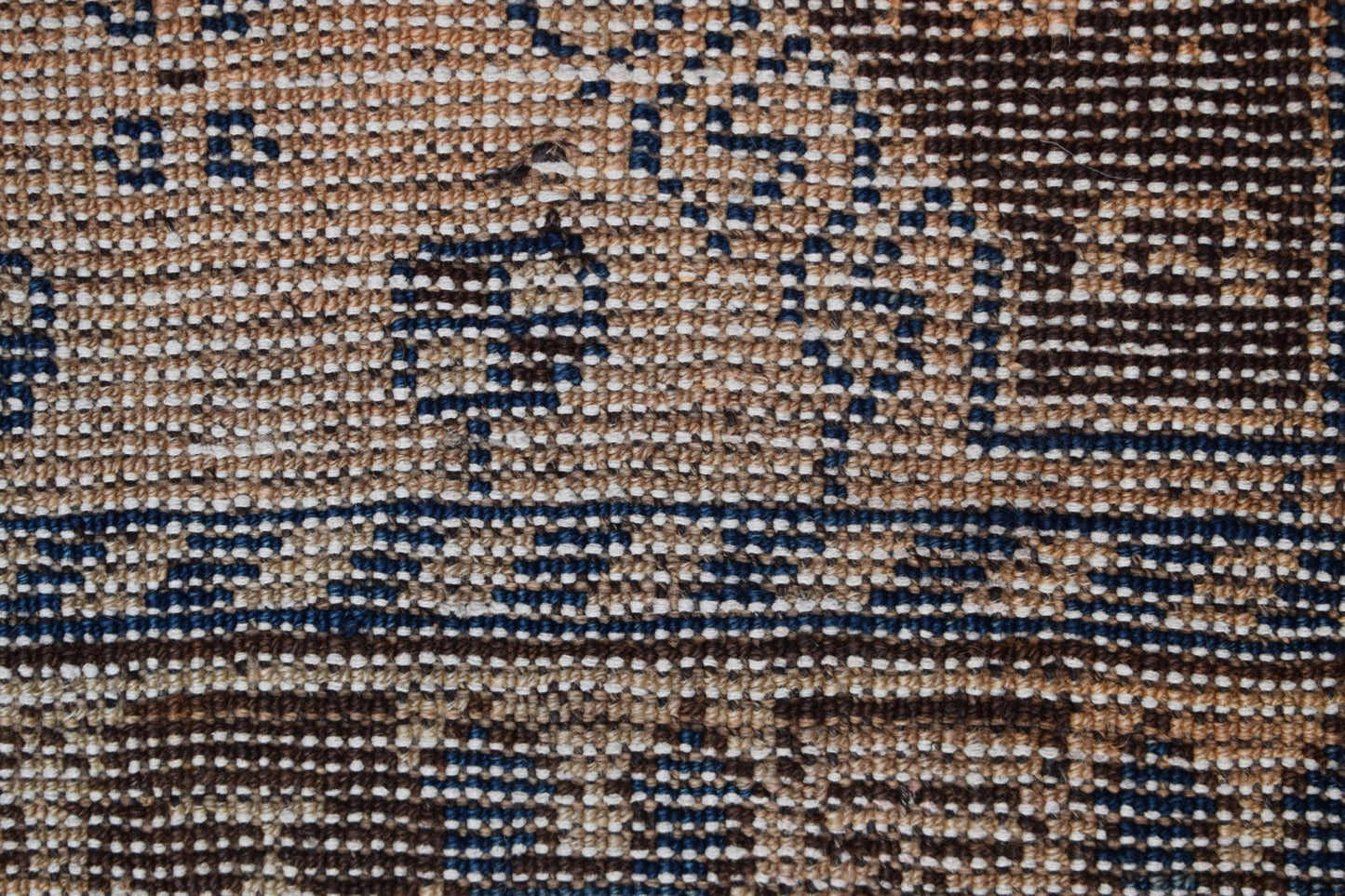 A close-up view of a vintage Afghan Baluch rug featuring a geometric pattern in brown and blue.