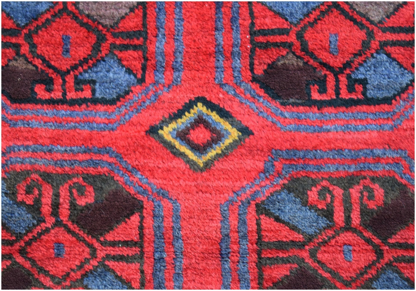 A vintage Afghan Baluch rug featuring a geometric pattern in red, blue, and dark brown wool.