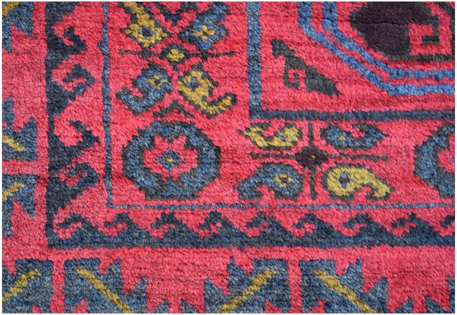 A close-up of a vintage Afghan Baluch rug featuring traditional geometric patterns in red and blue.