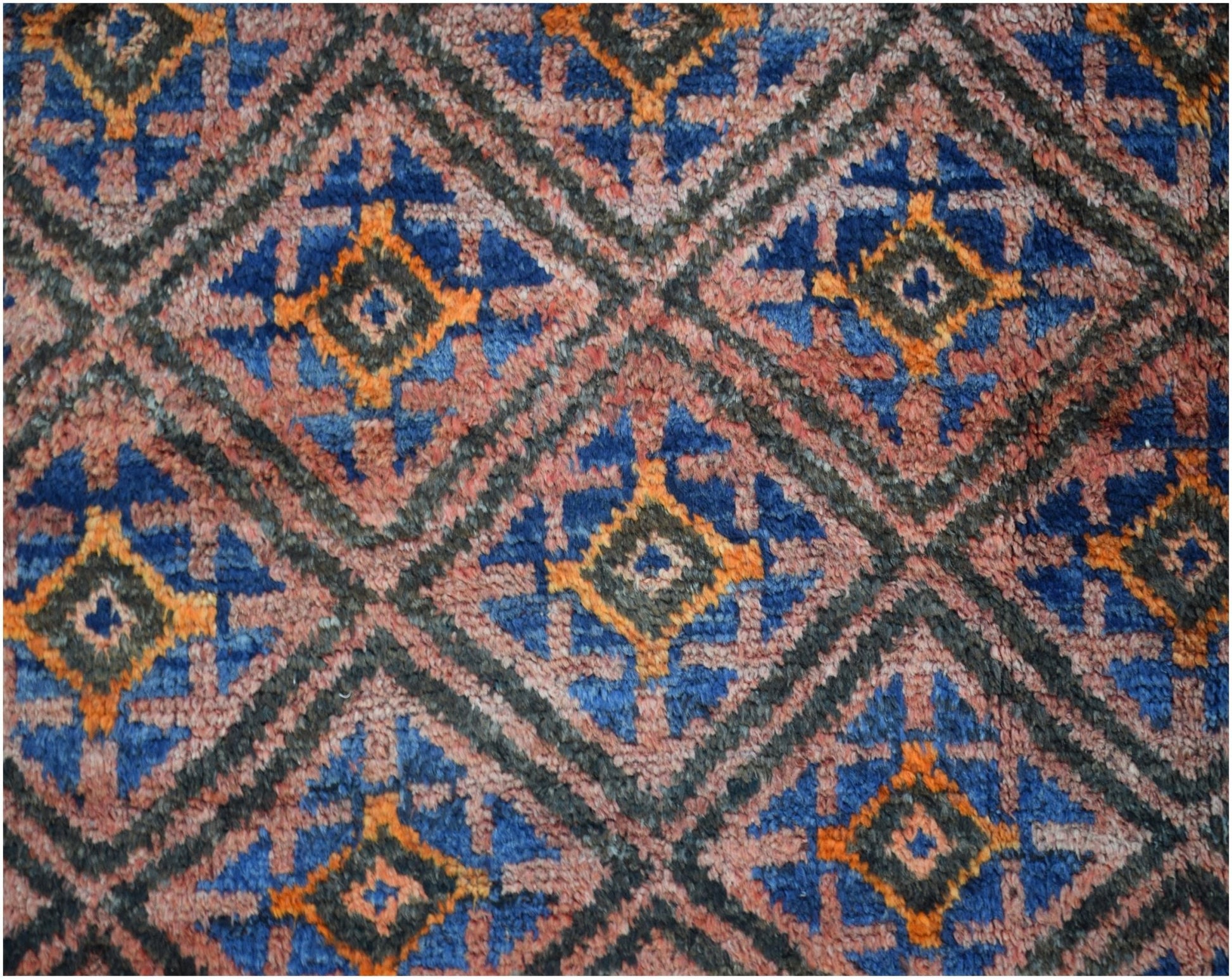 A vintage Afghan Baluch wool rug featuring a repeating diamond pattern in blue, orange, and pink.