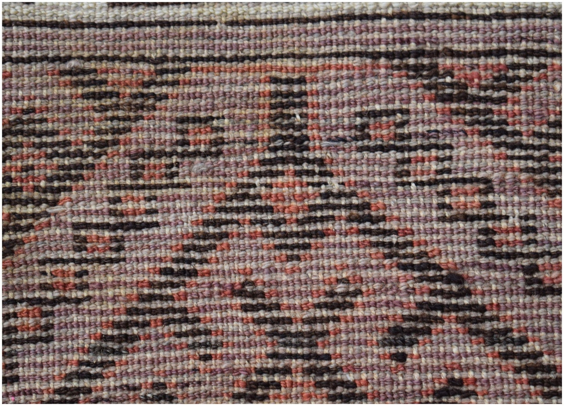A close-up view of a vintage Afghan Baluch rug featuring a geometric pattern in wool.