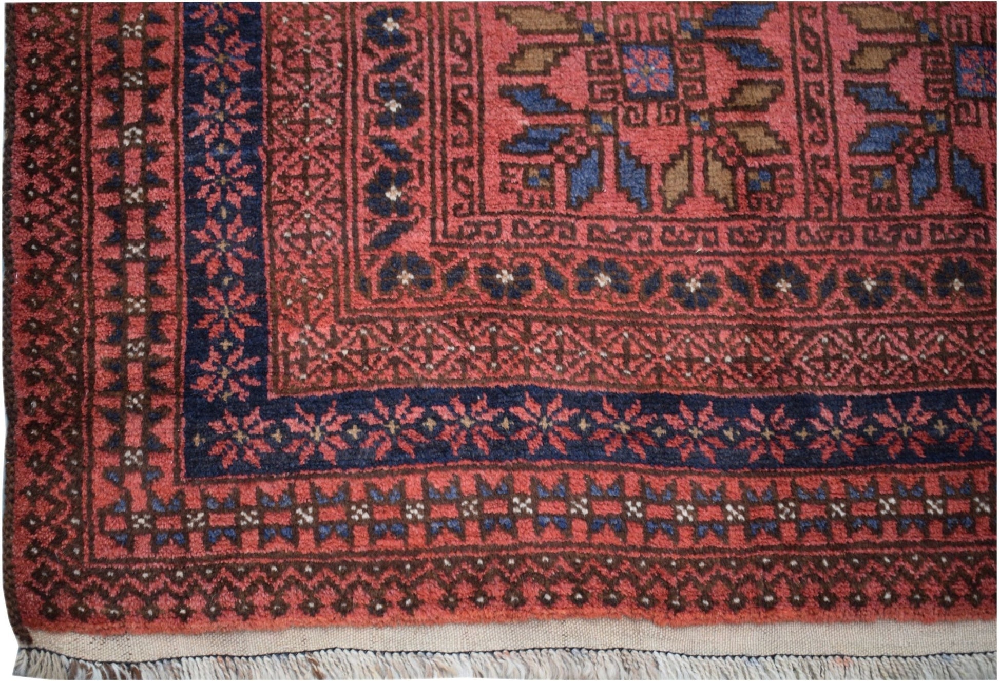 A vintage Afghan Baluch rug featuring a geometric pattern in red, blue, and brown wool.
