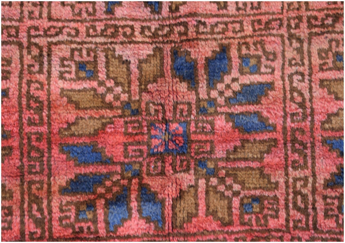 A vintage Afghan Baluch rug featuring a geometric floral pattern in red, blue, and brown wool.