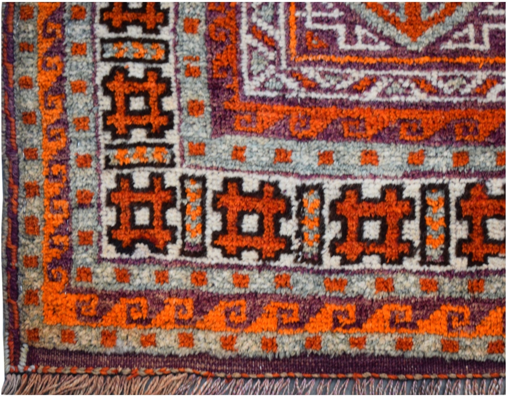 A close-up of a vintage Afghan Baluch rug featuring geometric orange and purple tribal patterns.