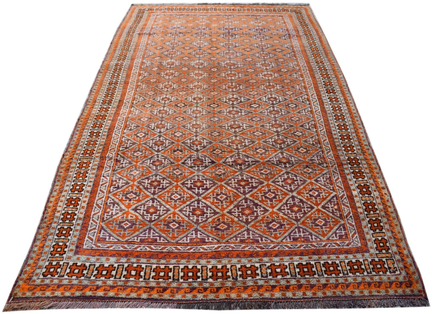 A vintage handmade Afghan Baluch rug featuring a repeating diamond pattern in orange and purple.