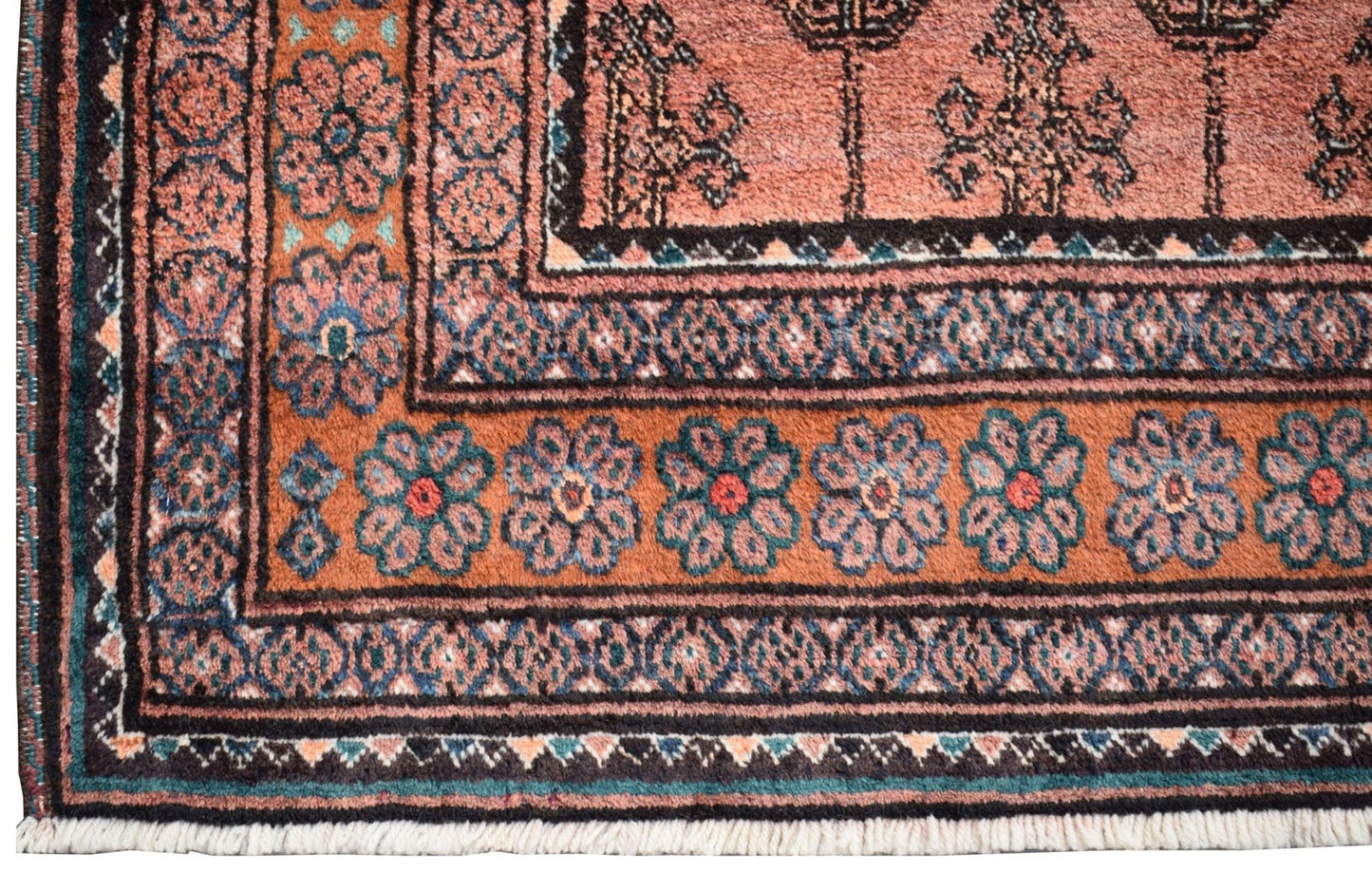 A vintage Afghan Baluch rug featuring a geometric floral border in rust, blue, and black wool.