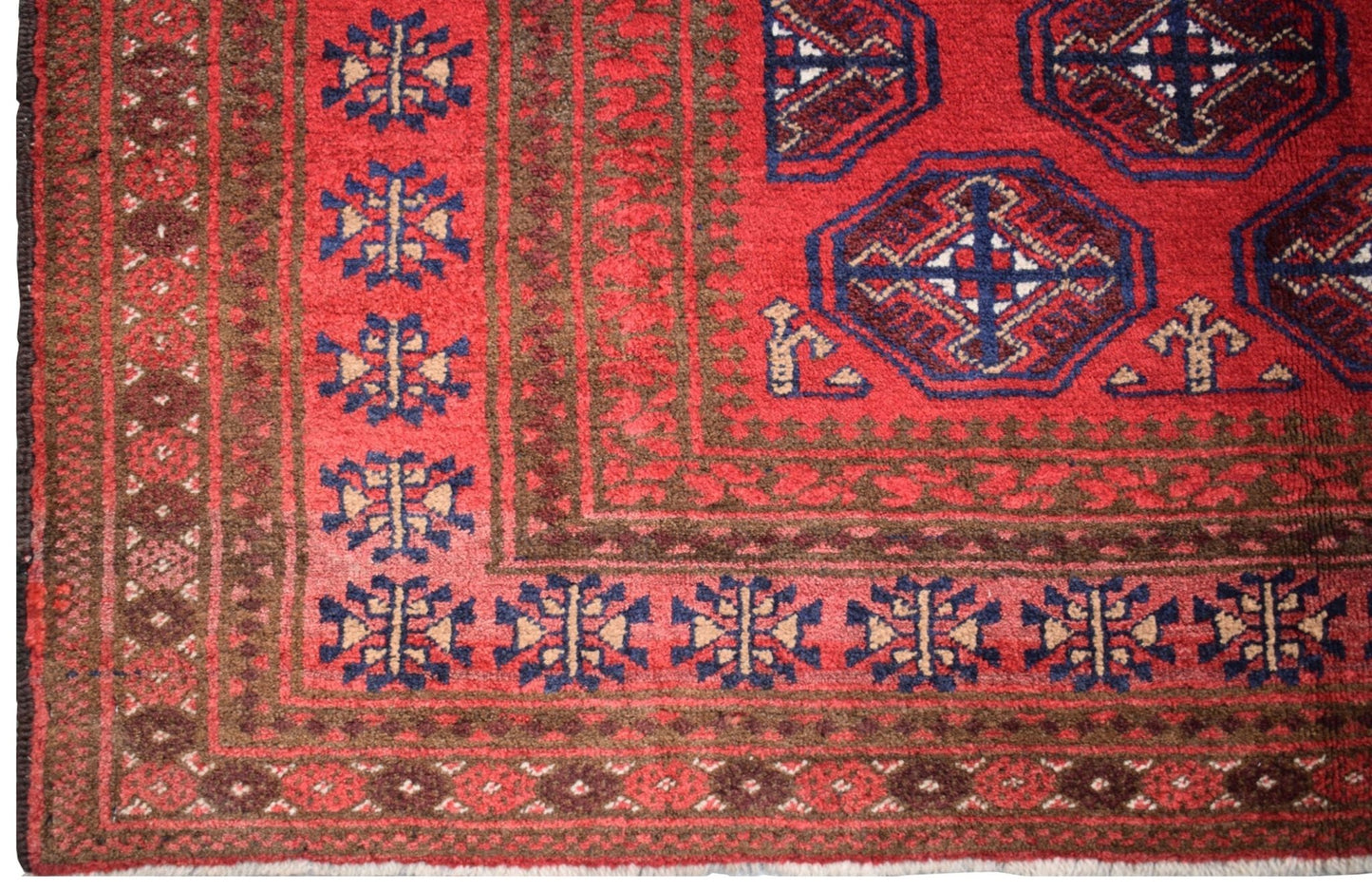 A vintage Afghan Baluch rug featuring a red field with geometric motifs and a dark border.
