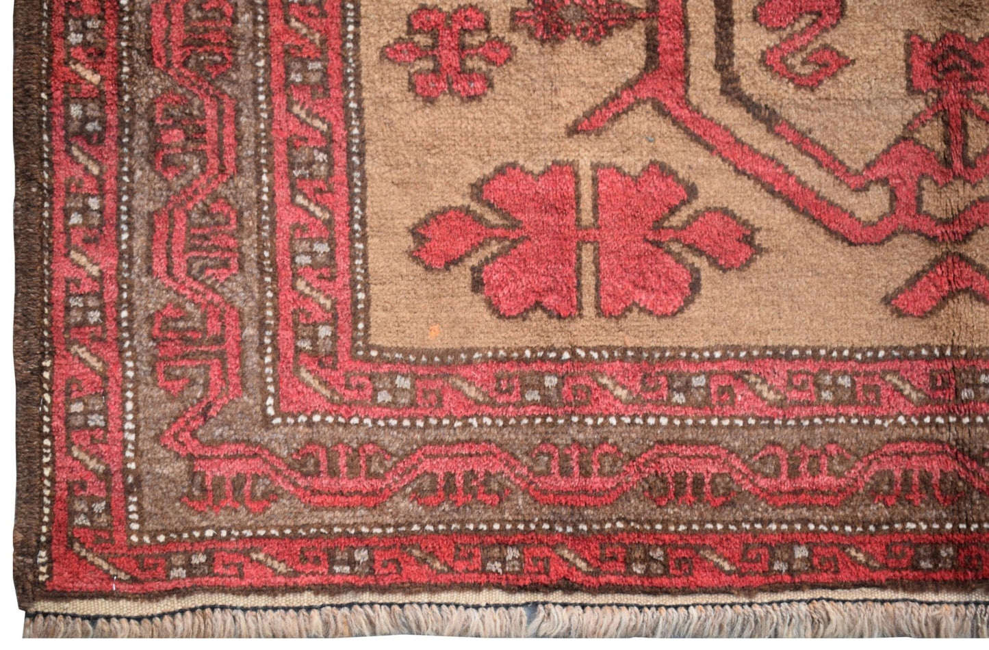 A vintage handmade Afghan Baluch rug featuring geometric red patterns on a brown wool field.