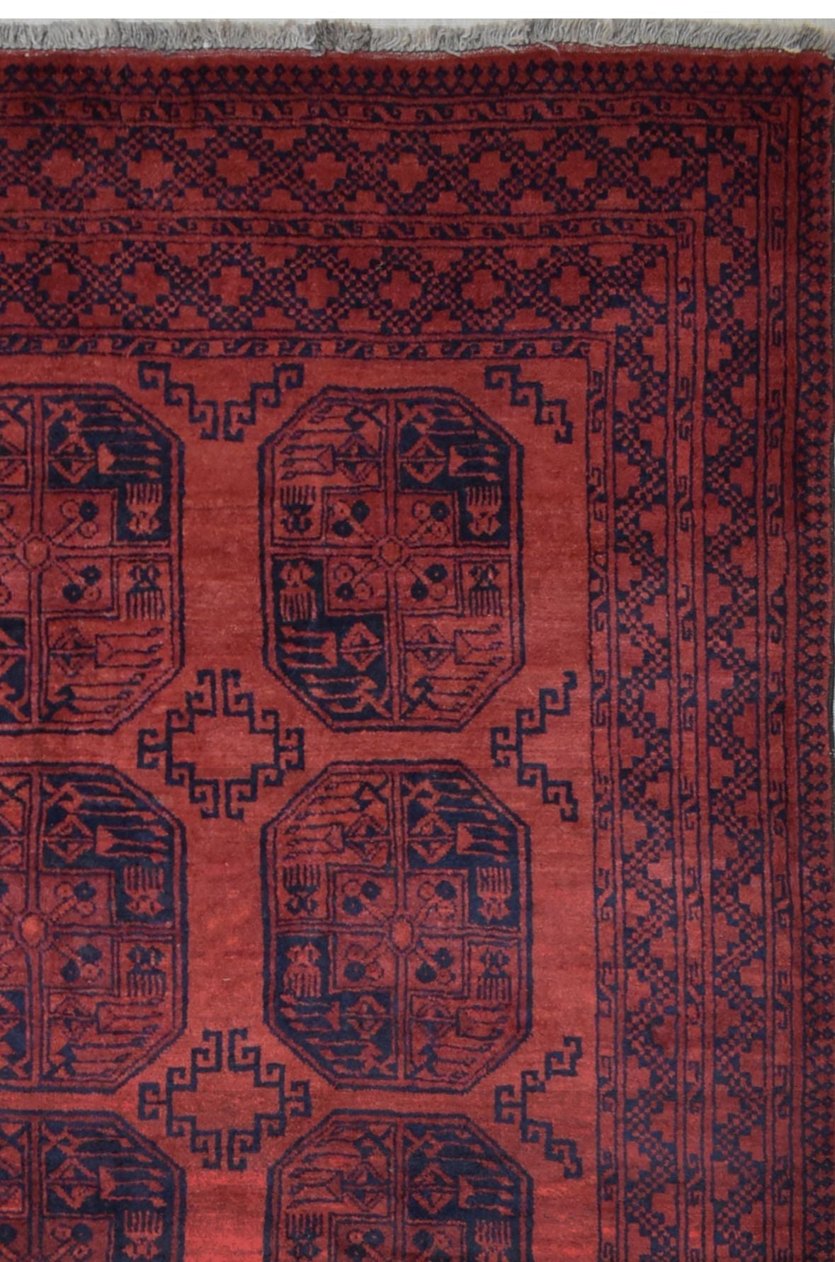 A vintage handmade Afghan Turkmen rug featuring geometric patterns in deep red and navy blue.
