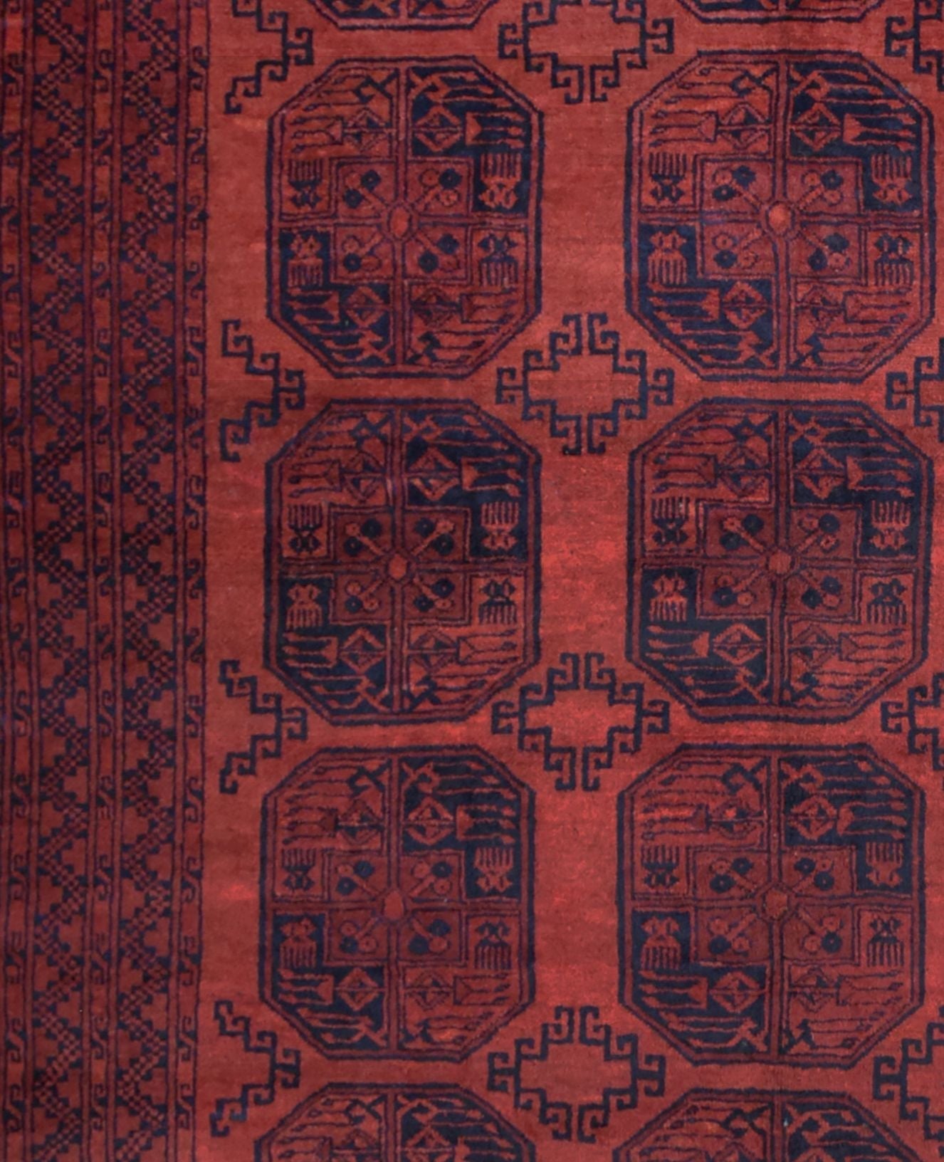 A vintage Afghan Turkmen rug featuring a repeating geometric octagonal pattern in red and navy.