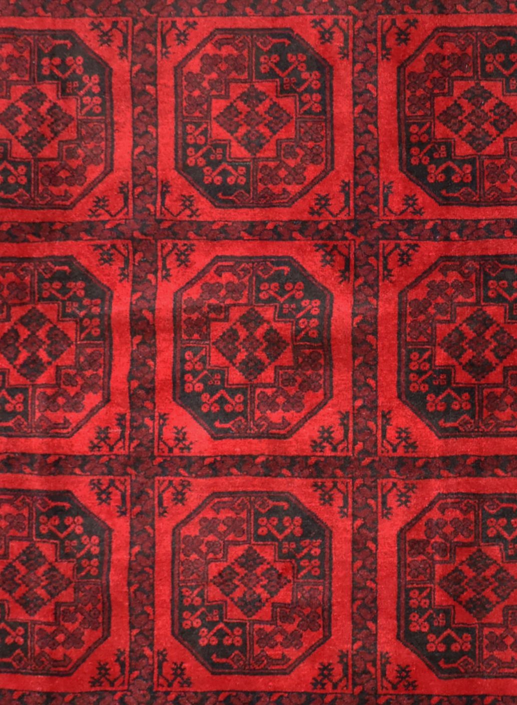 A vintage handmade Afghan Turkmen rug featuring a repeating geometric octagonal pattern in red.