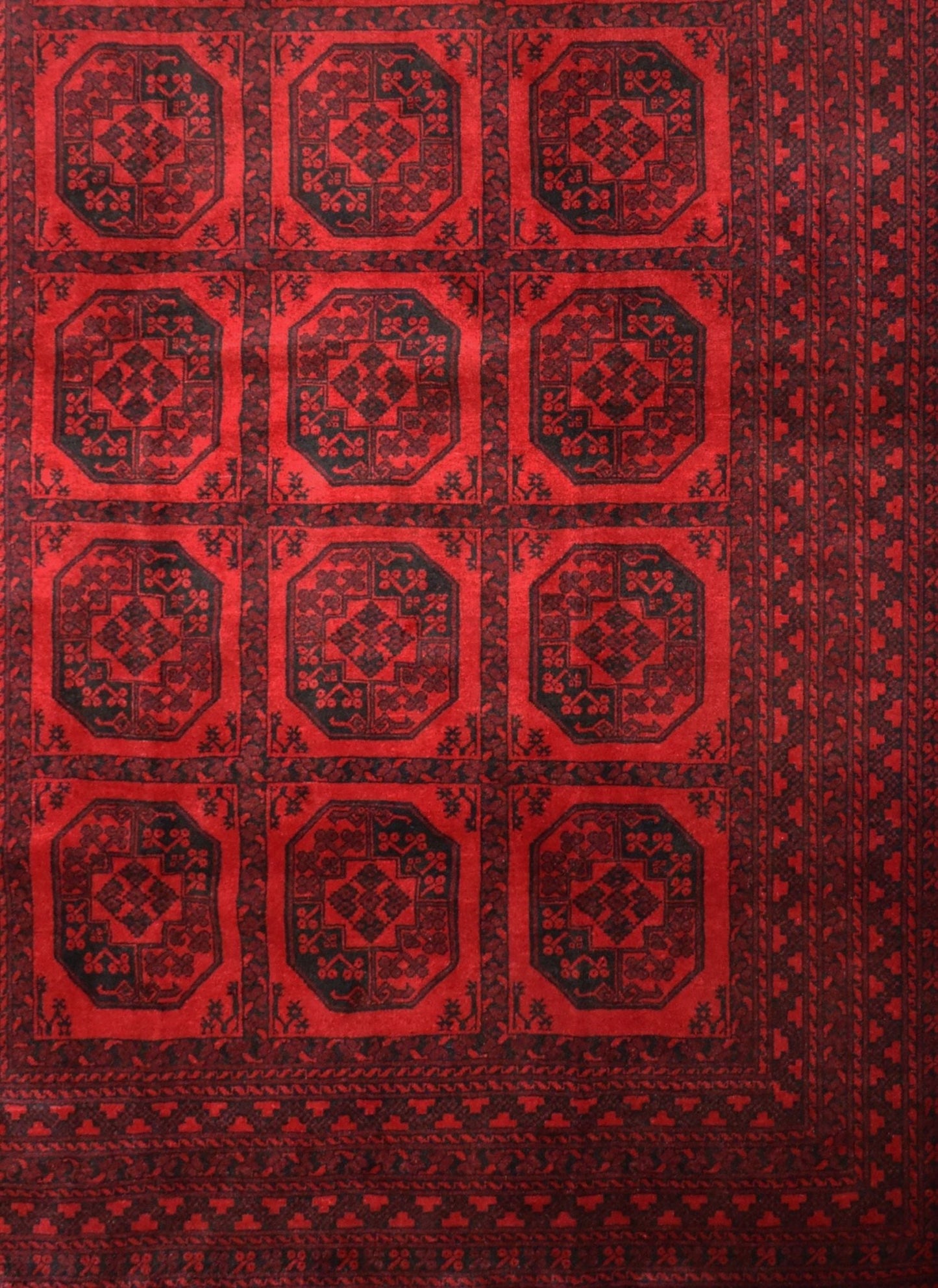 A vintage handmade Afghan Turkmen rug featuring a repeating geometric octagonal pattern in red.