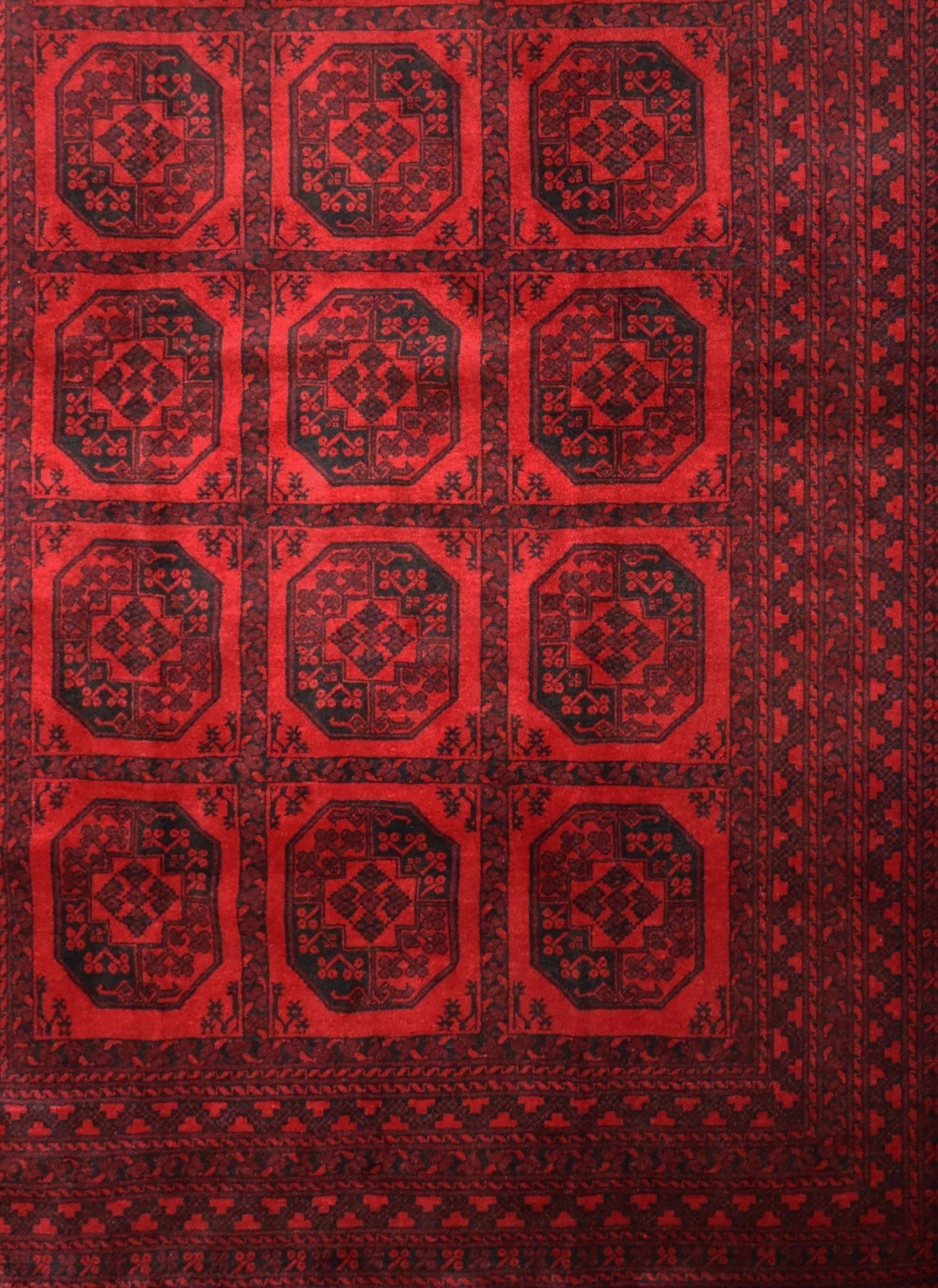 A vintage handmade Afghan Turkmen rug featuring a repeating geometric octagonal pattern in red.