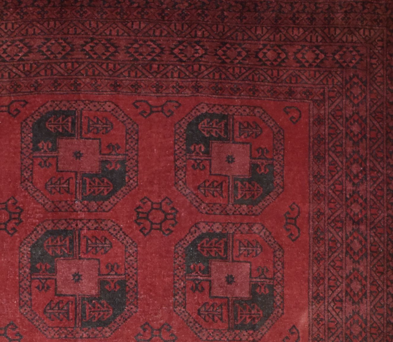 A vintage handmade Afghan Turkmen rug featuring a deep red field with repeating geometric motifs.