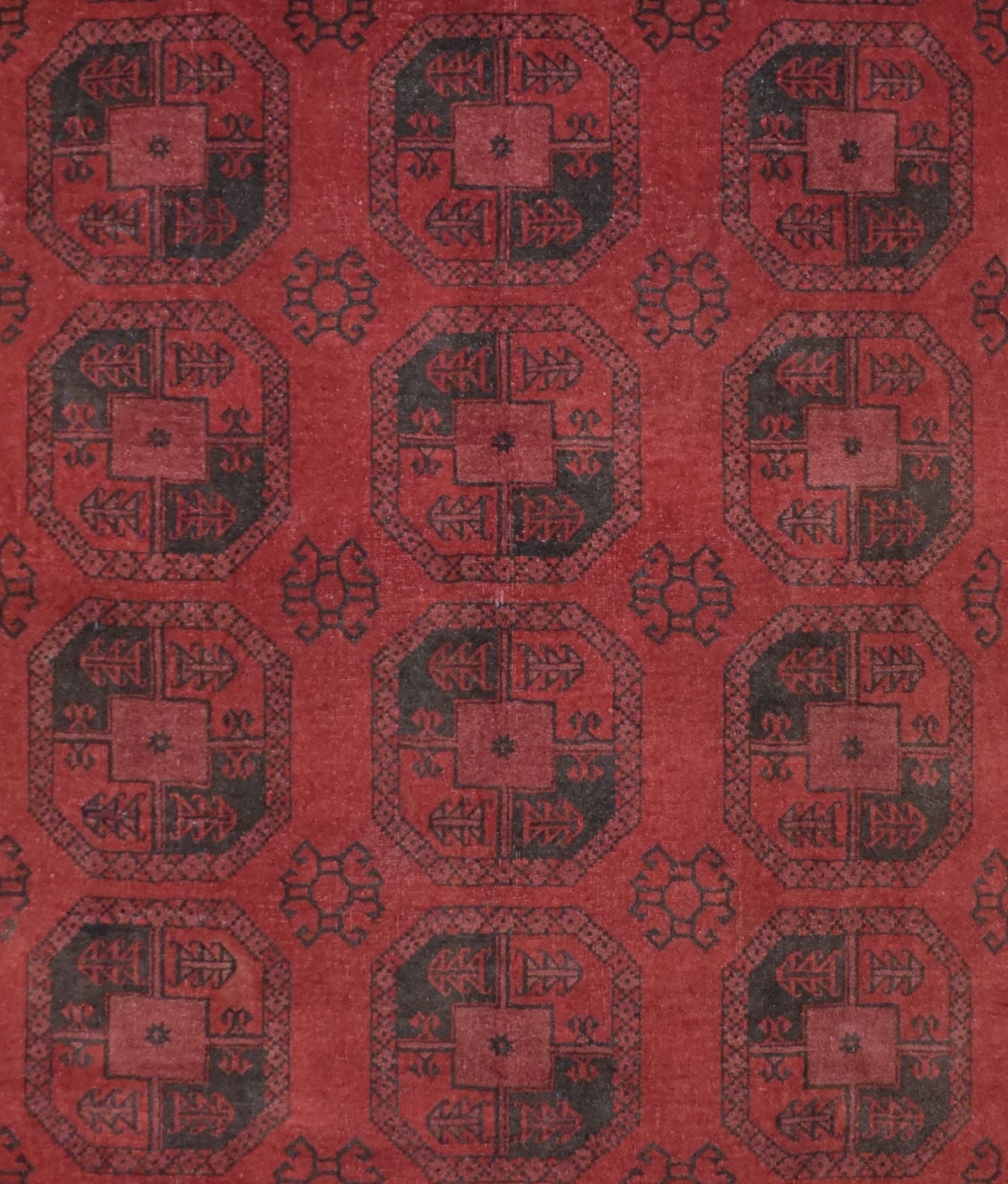 A vintage handmade Afghan Turkmen rug featuring a repeating geometric octagonal pattern in red and black.