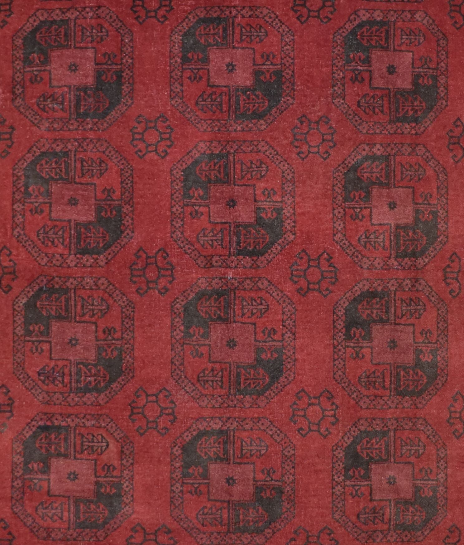 A vintage handmade Afghan Turkmen rug featuring a repeating geometric octagonal pattern in red and black.