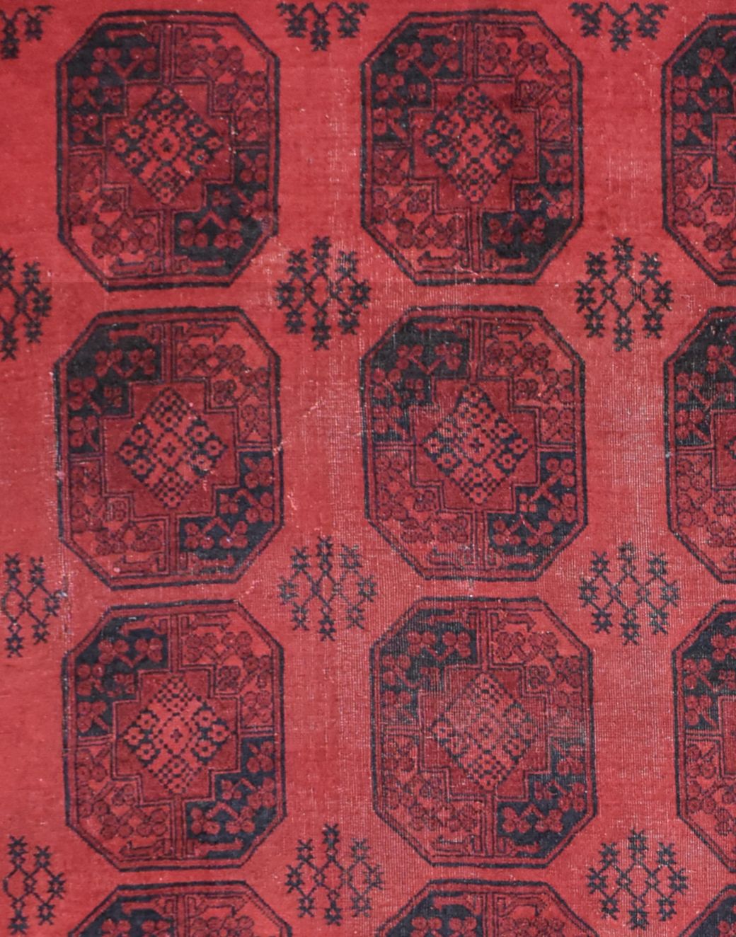 A vintage Afghan Turkmen rug featuring a repeating geometric gul pattern in deep red and black.