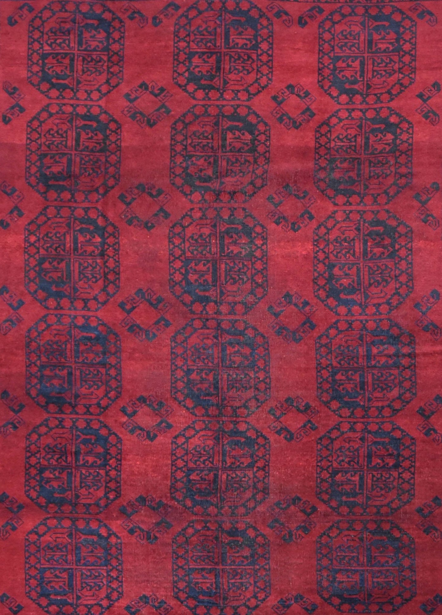 A vintage Afghan Turkmen rug featuring a repeating geometric pattern in deep red and dark blue.