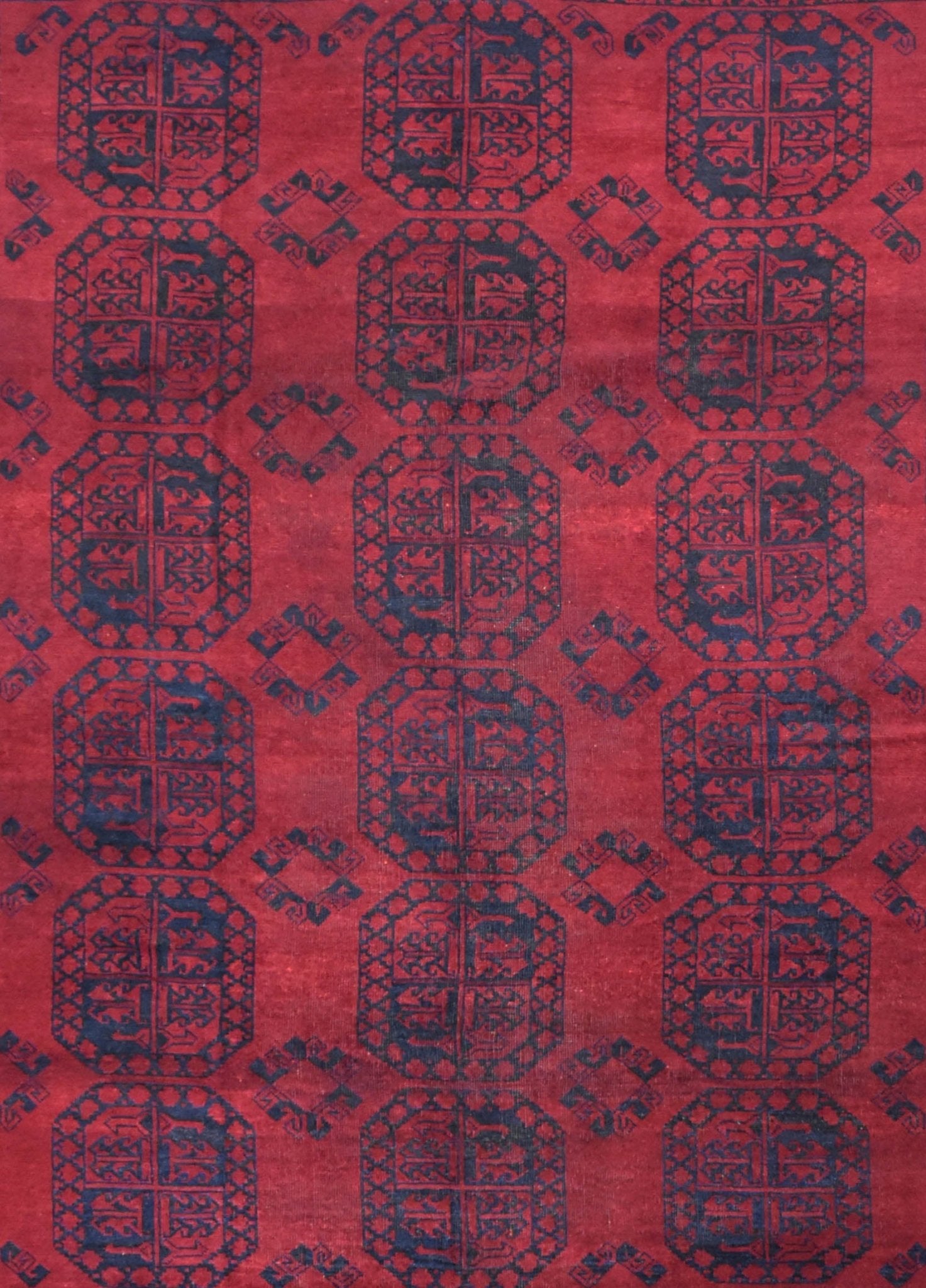 A vintage Afghan Turkmen rug featuring a repeating geometric pattern in deep red and dark blue.