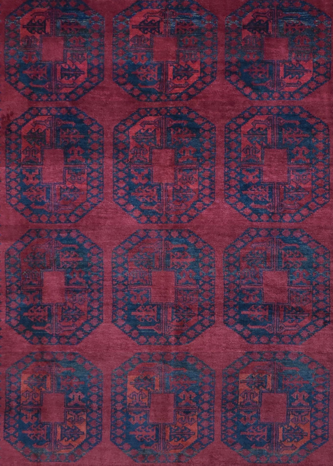 A vintage Afghan Turkmen rug featuring a repeating geometric pattern in deep red and blue tones.