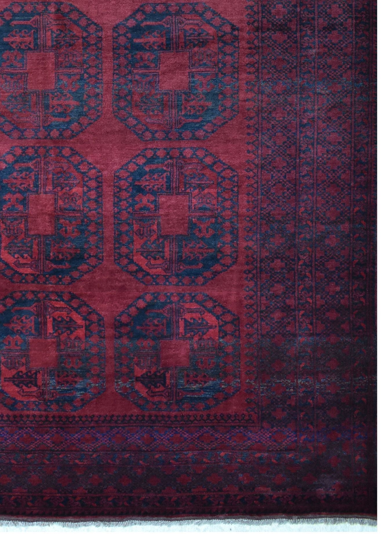 A vintage handmade Afghan Turkmen rug featuring repeating dark blue octagonal motifs on a red field.
