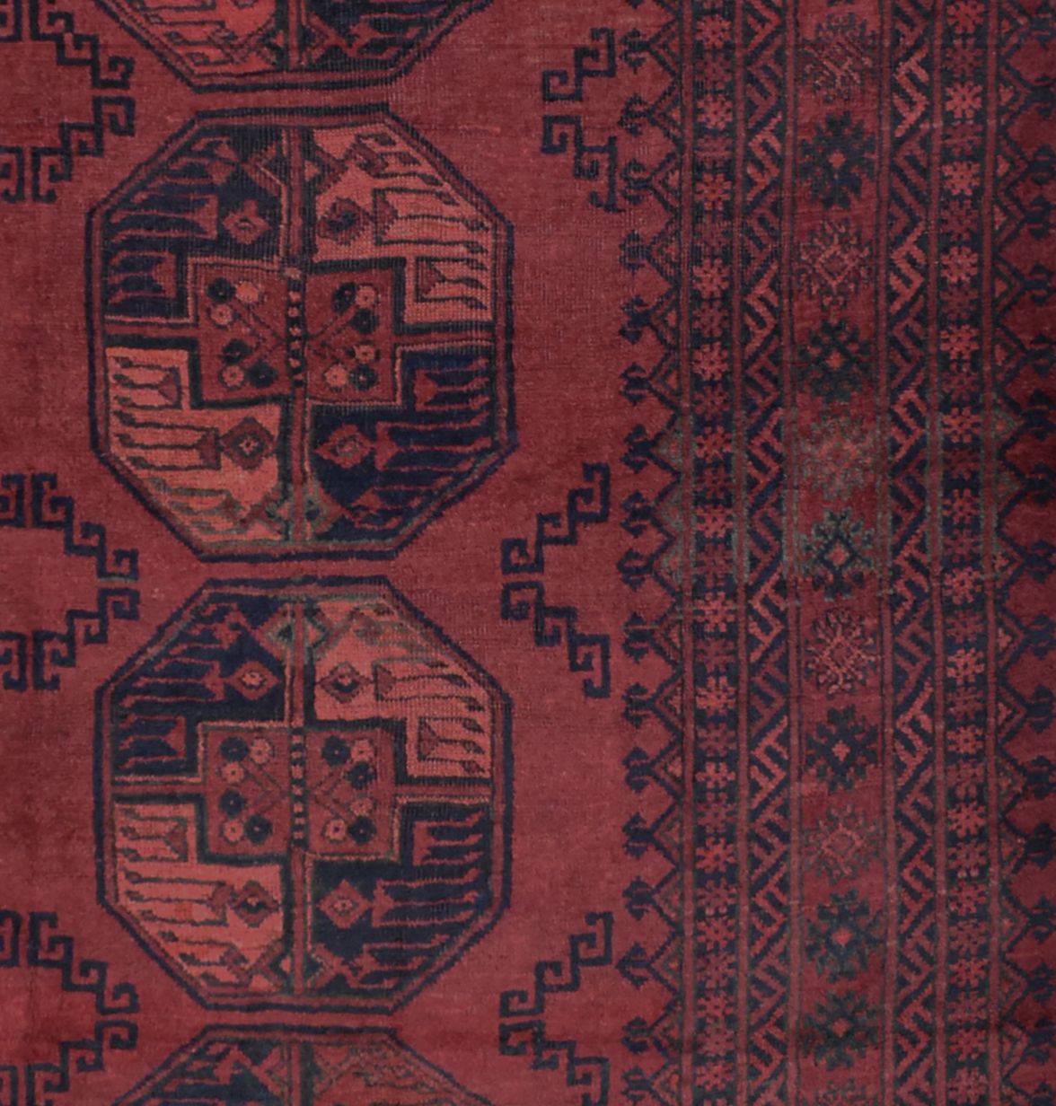 A vintage Afghan Turkmen rug featuring dark red tones and traditional geometric octagonal motifs.