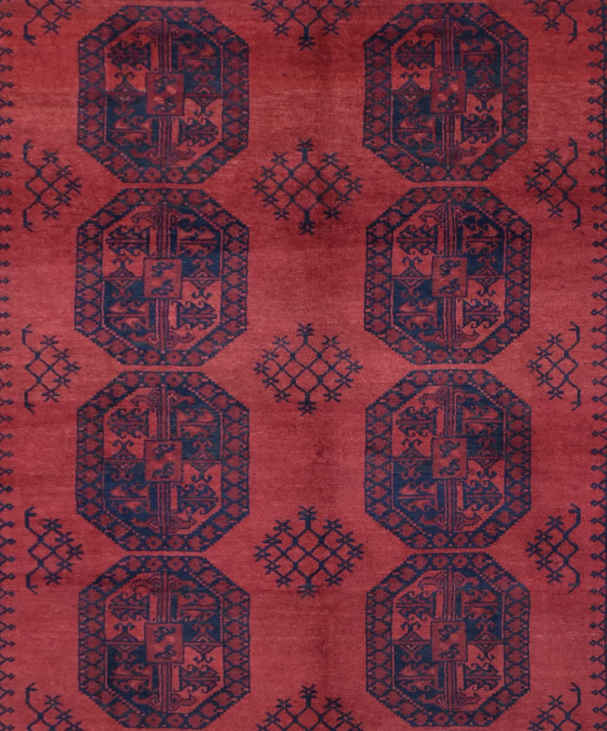 A vintage handmade Afghan Turkmen rug featuring repeating dark blue octagonal motifs on a red field.