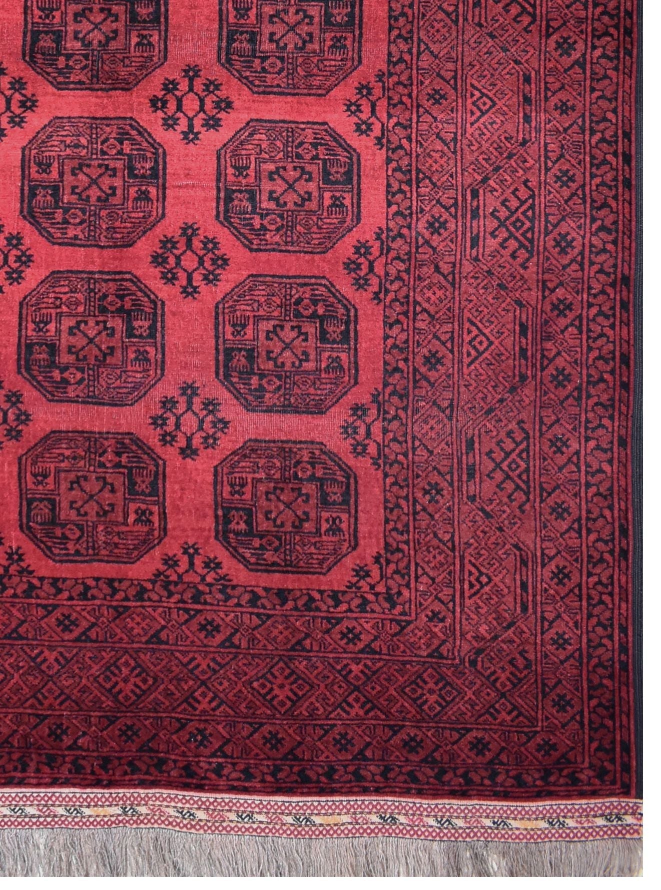 A vintage handmade Afghan Turkmen rug featuring geometric octagonal motifs in red and black wool.
