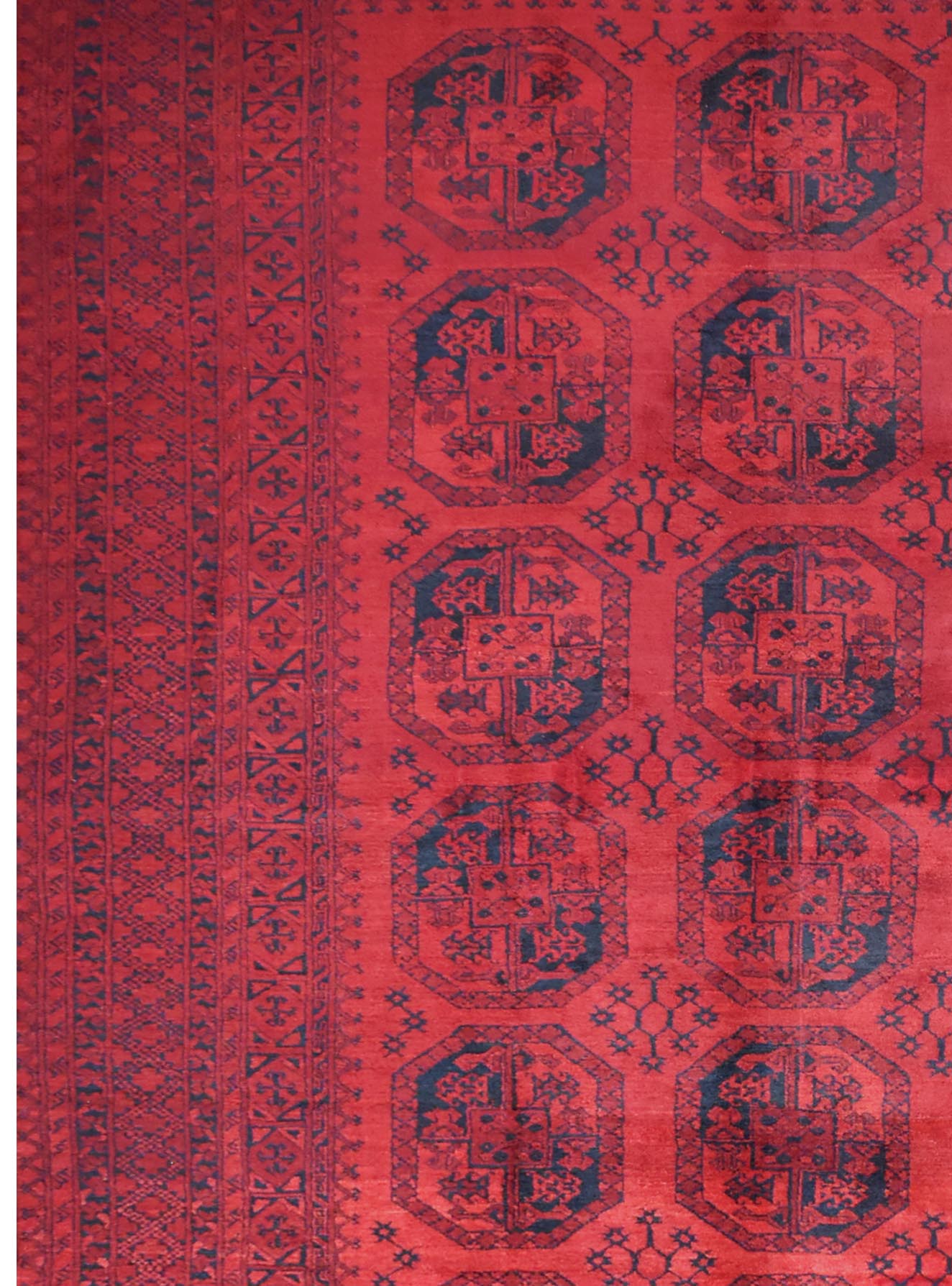 A vintage handmade Afghan Turkmen rug featuring repeating dark octagonal motifs on a red field.
