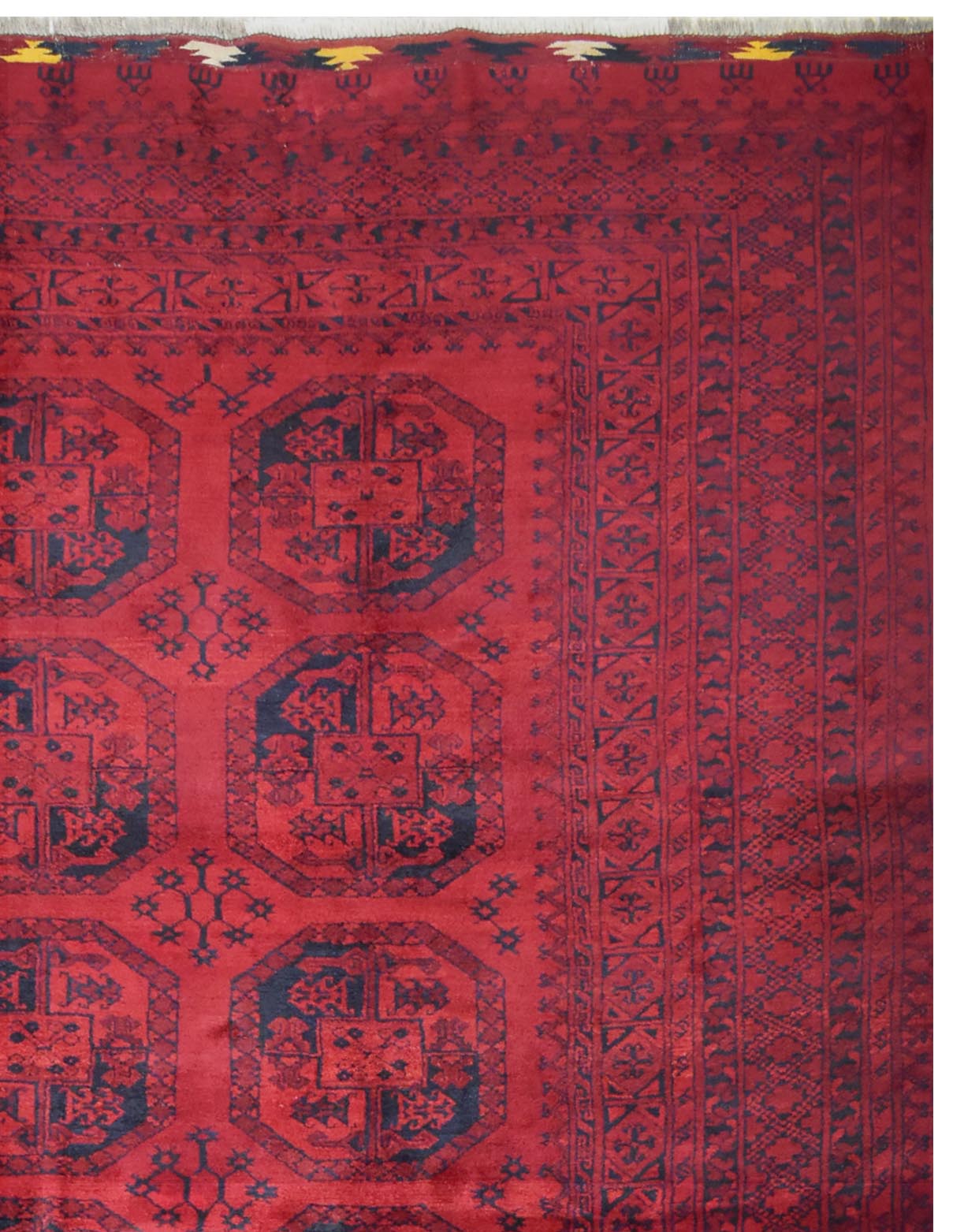 A vintage handmade Afghan Turkmen rug featuring repeating dark octagonal motifs on a red field.