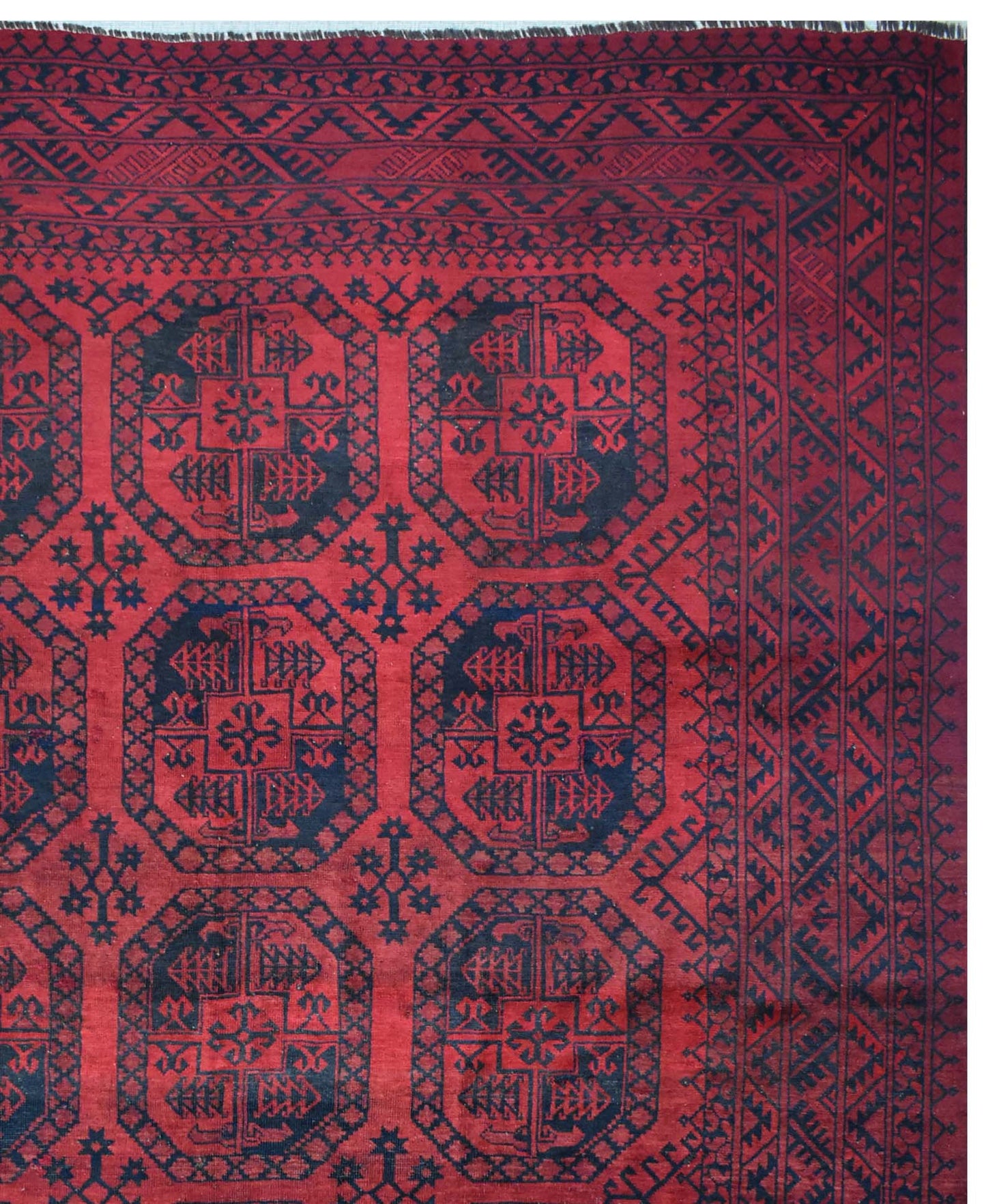 A vintage Afghan Turkmen rug featuring a repeating geometric octagonal pattern in red and black.
