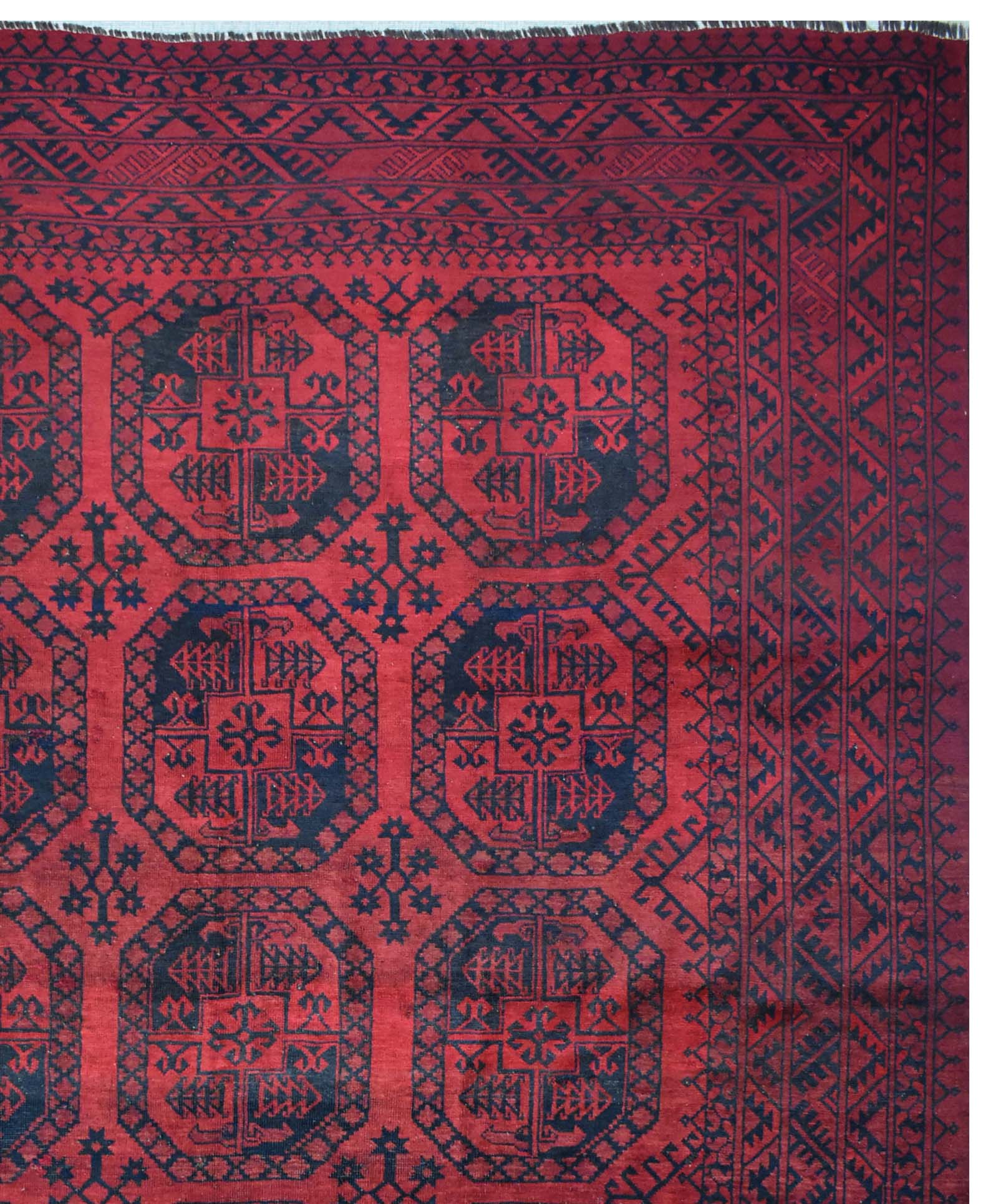 A vintage Afghan Turkmen rug featuring a repeating geometric octagonal pattern in red and black.