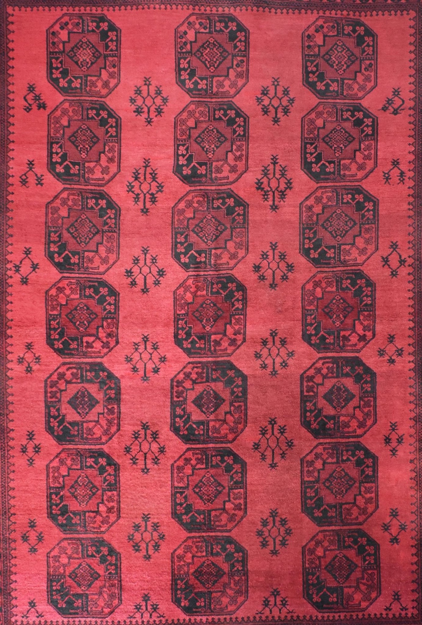 A vintage handmade Afghan Turkmen rug featuring repeating octagonal motifs in deep red and black.
