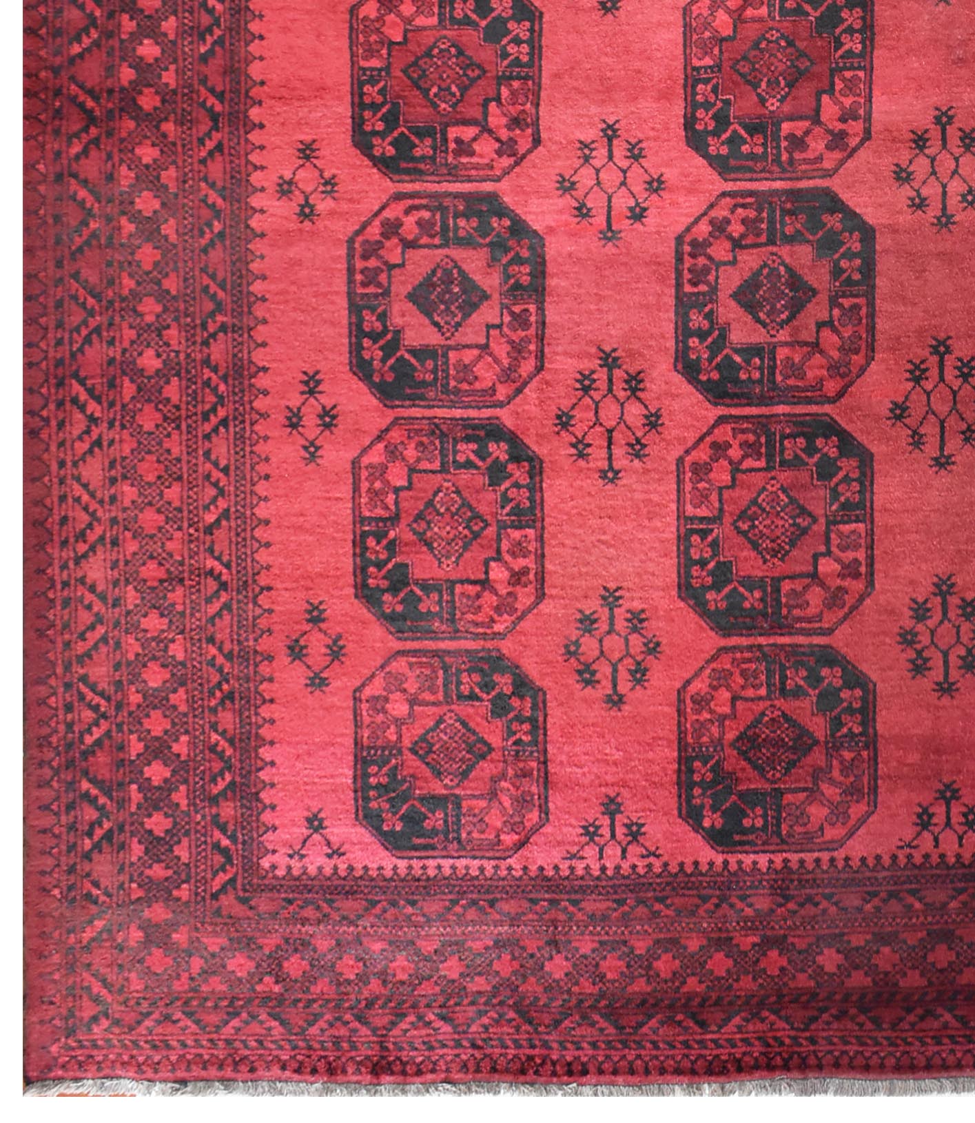 A vintage handmade Afghan Turkmen rug featuring repeating dark octagonal motifs on a red field.