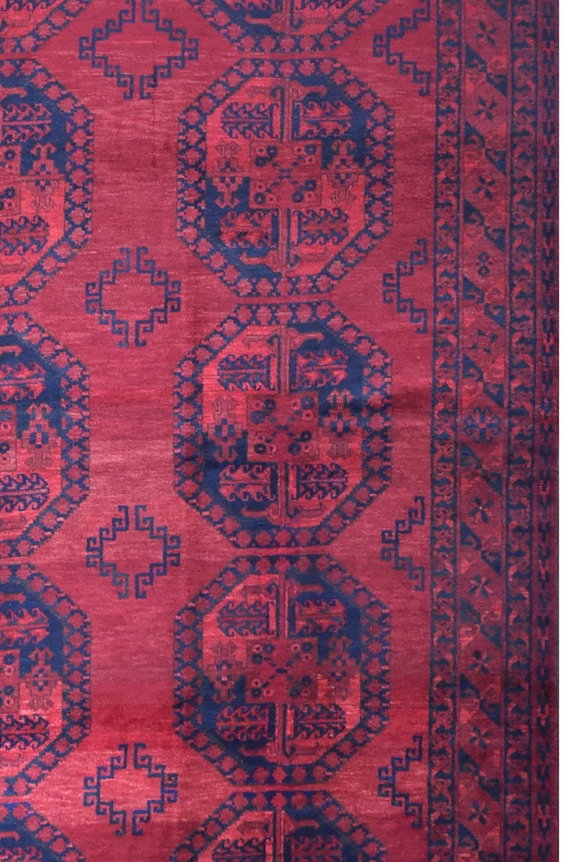 A vintage handmade Afghan Turkmen rug featuring repeating dark blue octagonal motifs on a red field.