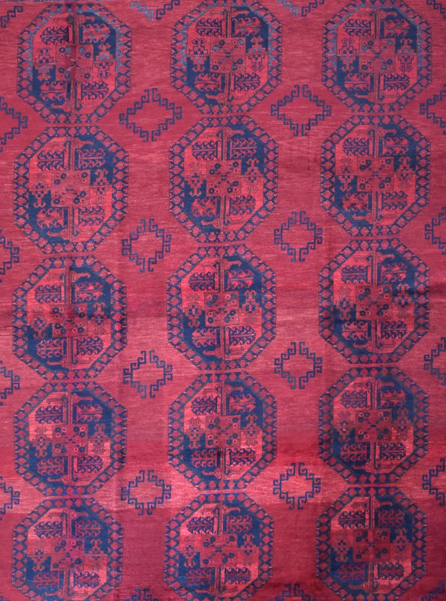 A vintage Afghan Turkmen rug featuring a repeating geometric octagonal pattern in red and navy blue.