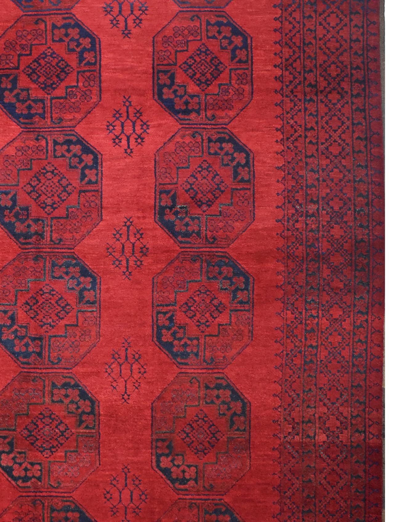 A vintage handmade Afghan Turkmen rug featuring repeating dark blue octagonal motifs on a red field.