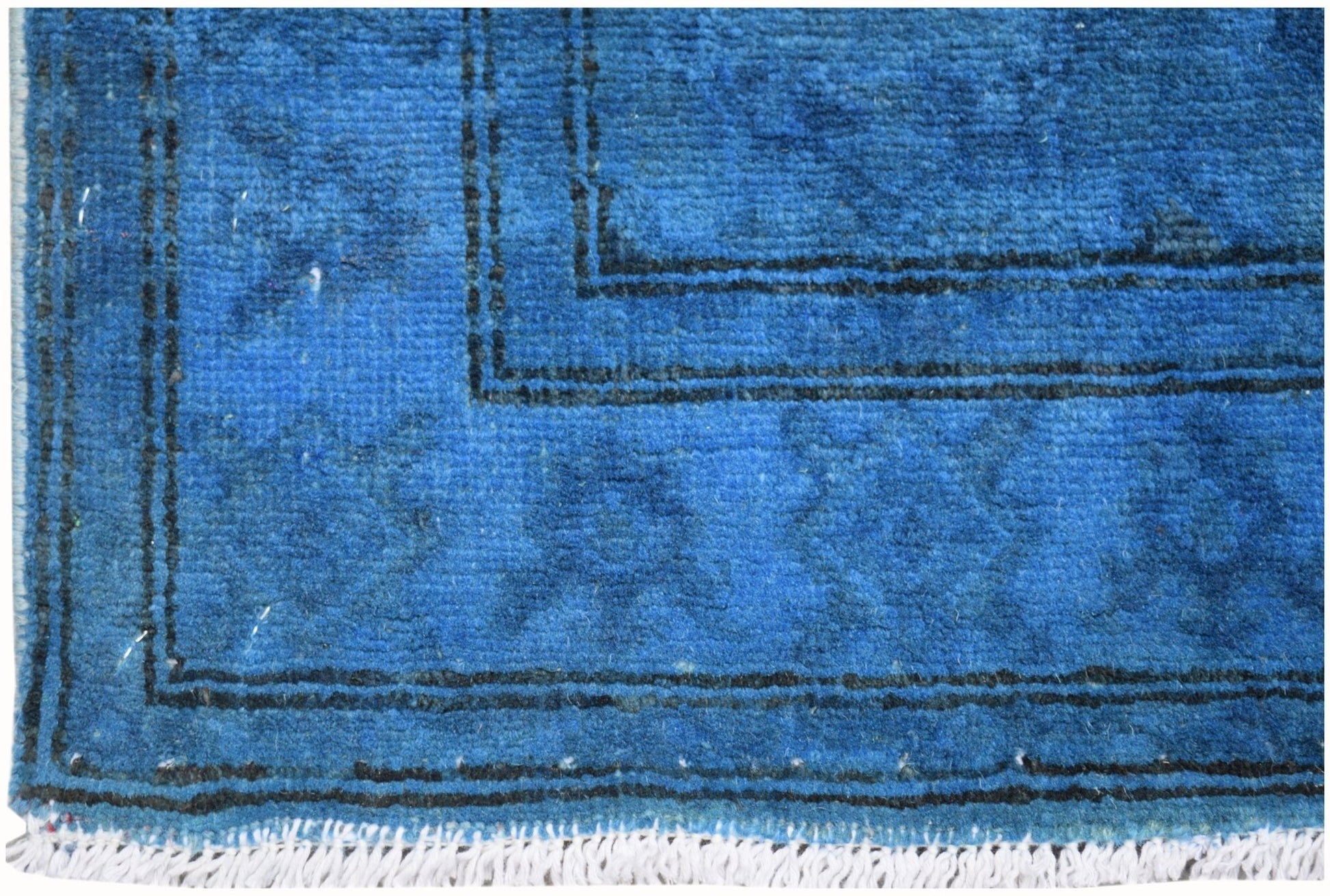 A close-up of a vibrant blue overdyed Afghan Chobi runner with black border details and white fringe.