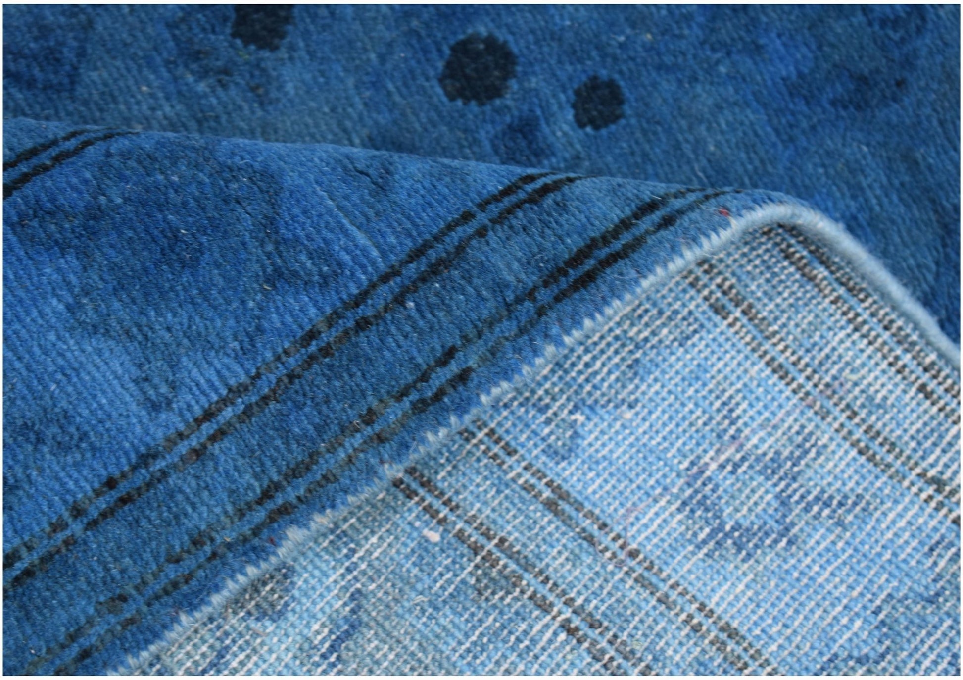 A close-up view of a blue overdyed Afghan Chobi runner showing its wool texture and backing.