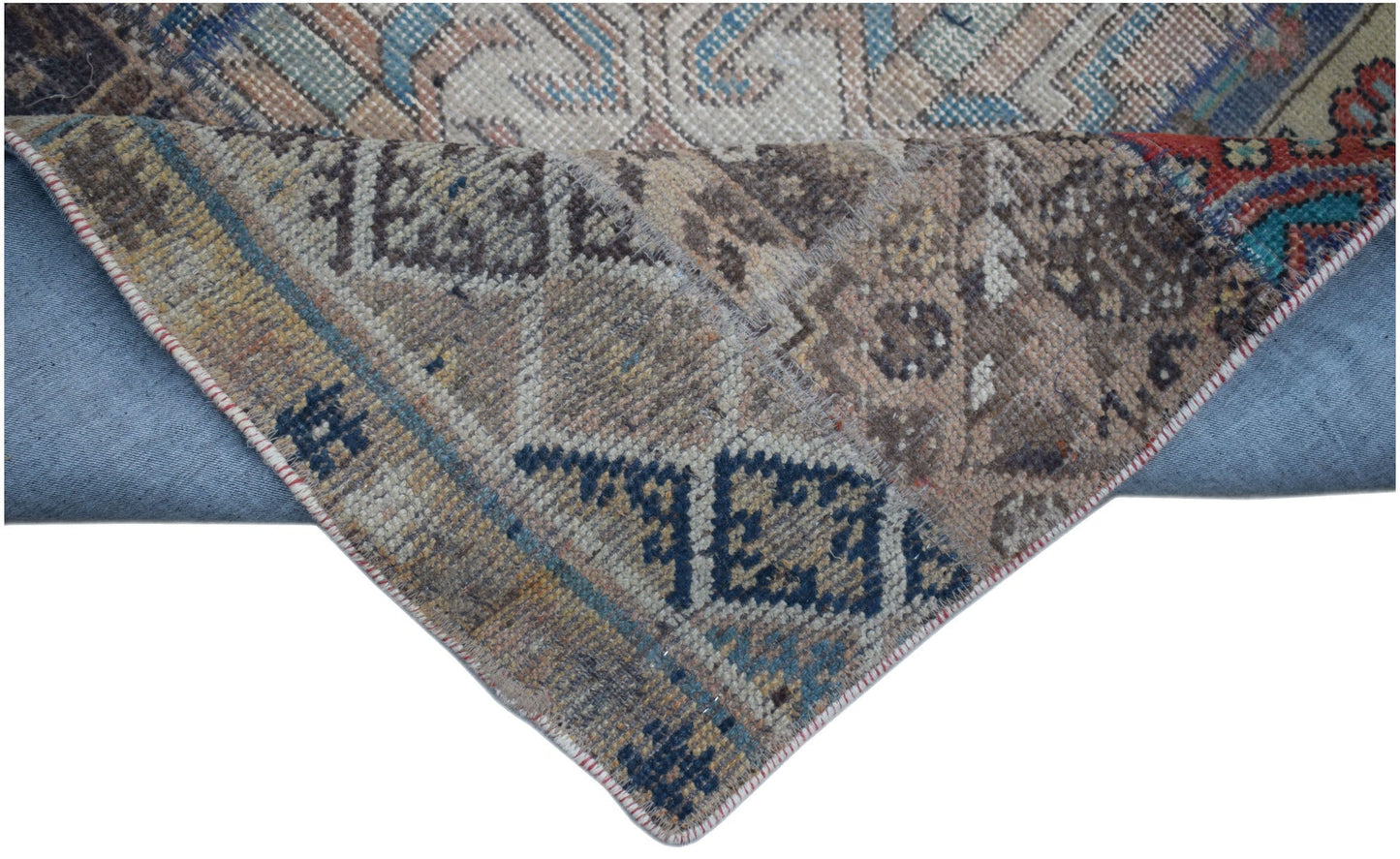 A handmade vintage patchwork runner featuring intricate wool patterns in blue and earth tones.
