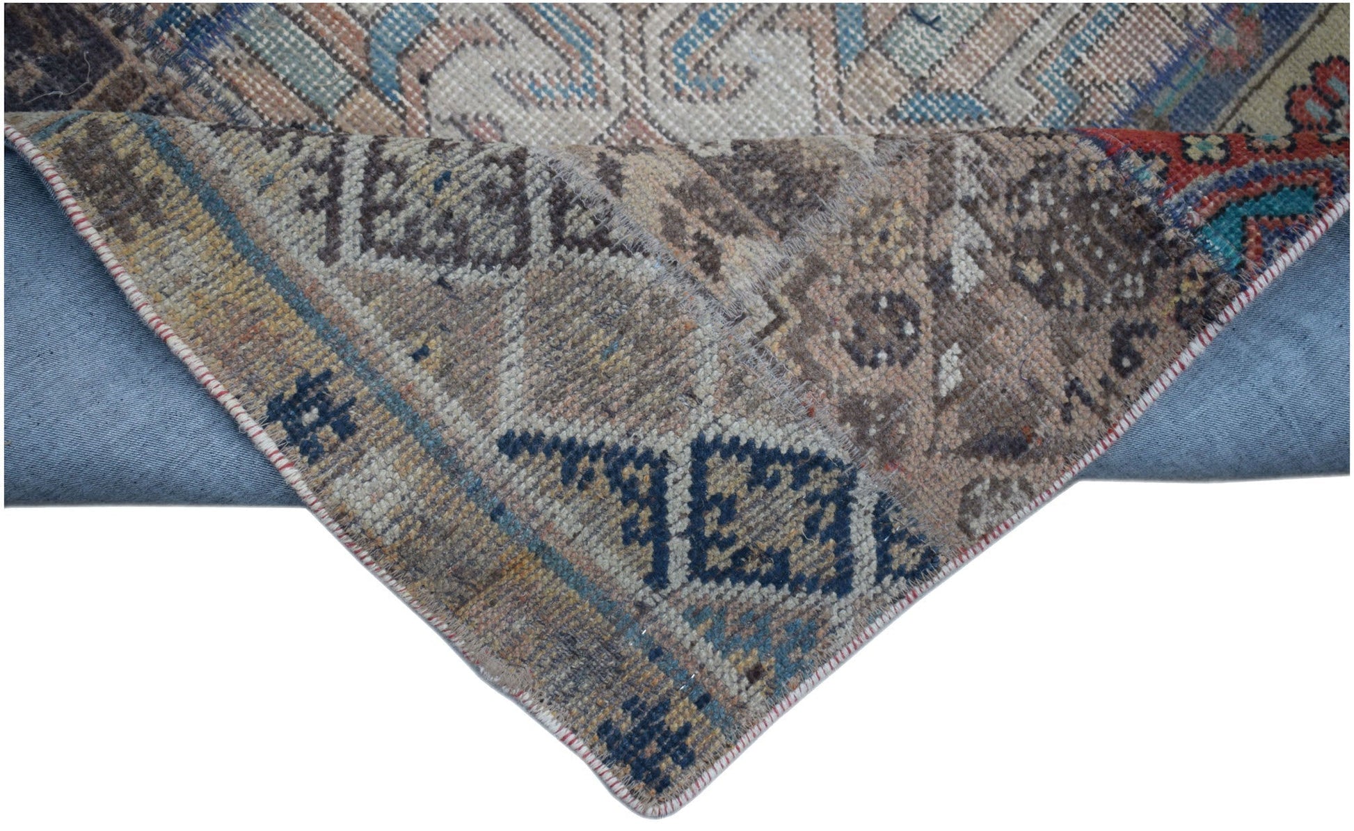 A handmade vintage patchwork runner featuring intricate wool patterns in blue and earth tones.