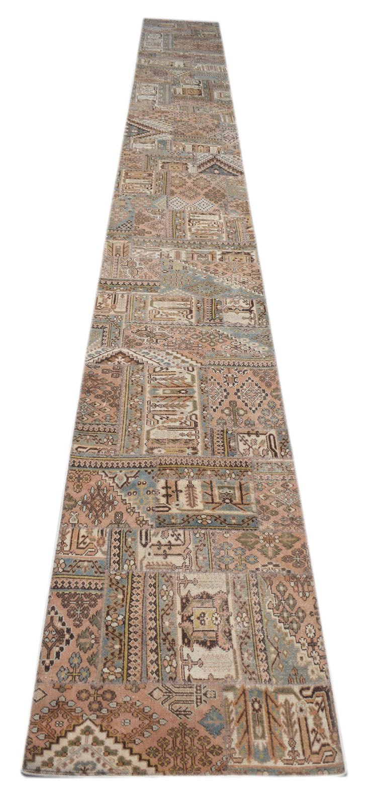 A long, handmade vintage patchwork runner rug featuring a variety of muted, multi-colored patterns.