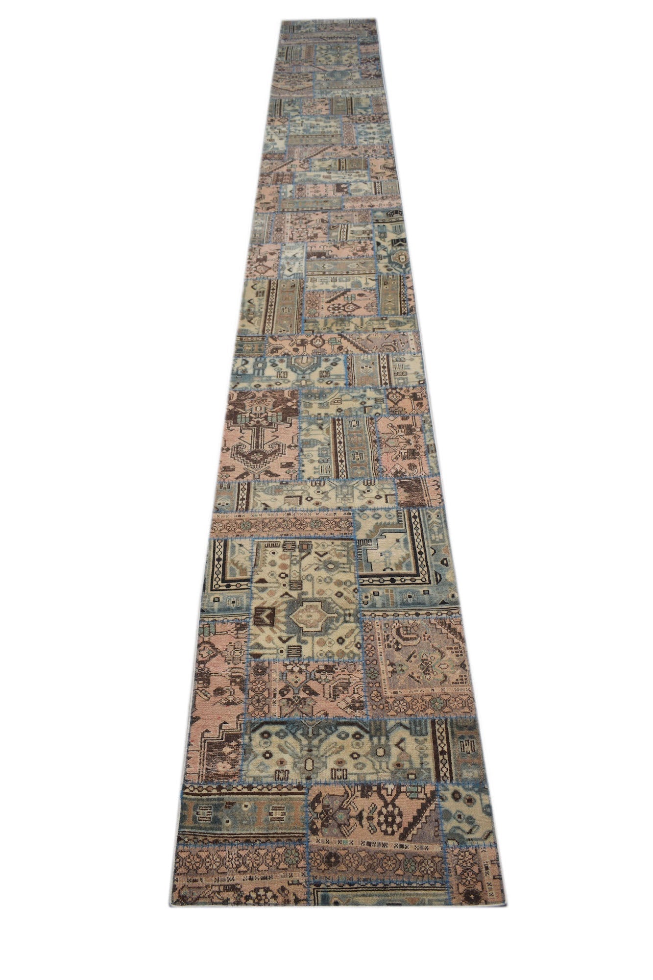 A long, handmade vintage patchwork runner rug featuring a variety of faded geometric patterns.