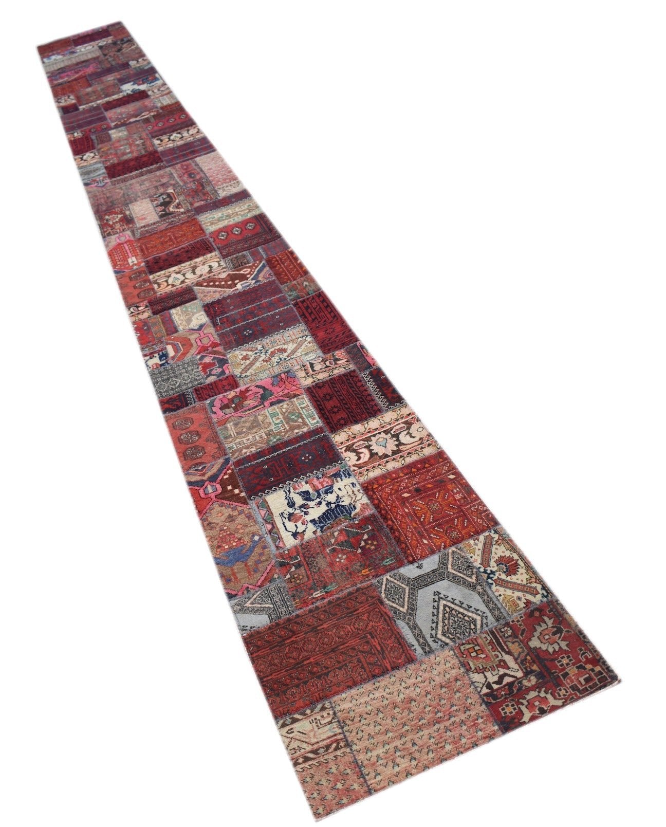 A long, handmade vintage patchwork runner rug featuring a variety of colorful wool patterns.